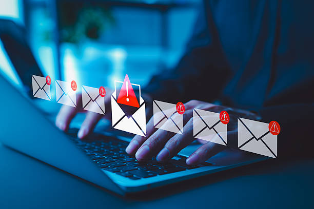 email security threat notification and spam warning concept. a person using laptop with icons of mail envelopes showing red warning symbols represents potential email security threats and spam alerts. - phishing stockfoto's en -beelden