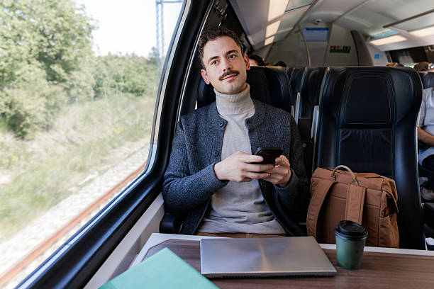 istock Businessman using mobile phone on a train journey with scenic background 2220462890