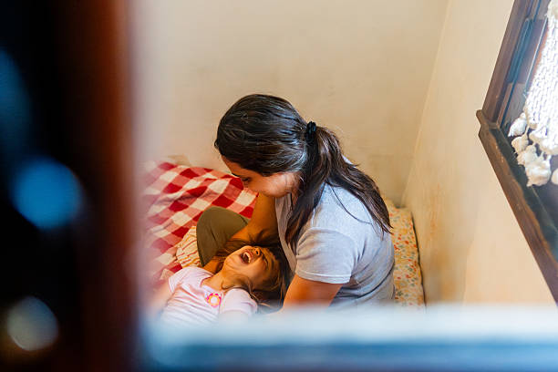 istock Mother and daughter having fun on bed at home 2220464075