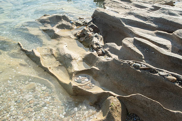 Beautiful eroded stone on calm sea waters on sunny summer day on the beach closeup