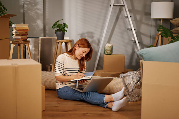 istock Woman organizing her move to new home using laptop and notebook 2220465570