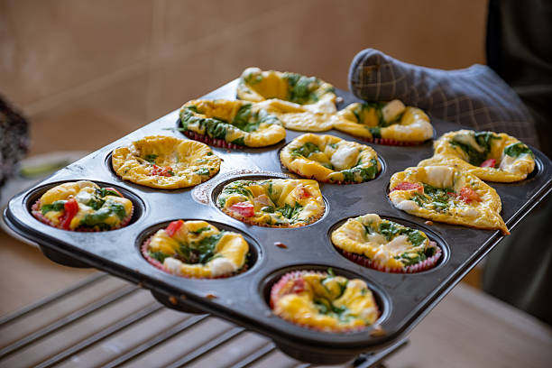 A tray of delicious homemade egg muffins filled with spinach, colorful vegetables, and cheese, freshly baked for a wholesome breakfast or snack option.