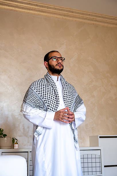 Man in Traditional Attire Standing Calmly in a Modern Interior Room