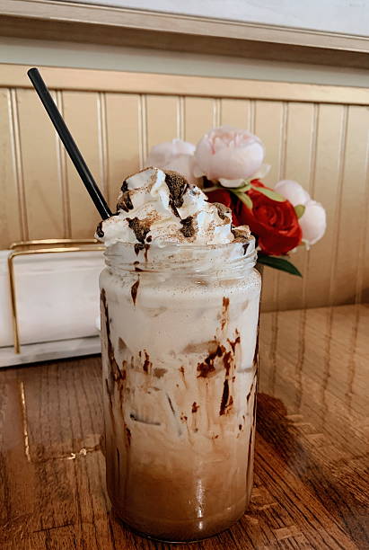 Delightful Cold Chocolate Cinnamon, Iced Latte with Whipped Cream & Chocolate Drizzle with a Vase of Pink & Red Roses & Napkins in the Background at a Cafe in West Palm Beach, Florida, in June of 2025