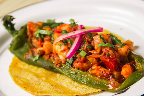 istock This delightful dish showcases a shrimp-stuffed chile, beautifully garnished with fresh herbs and onions, bringing together delicious flavors in a traditional Mexican culinary style. 2220466945