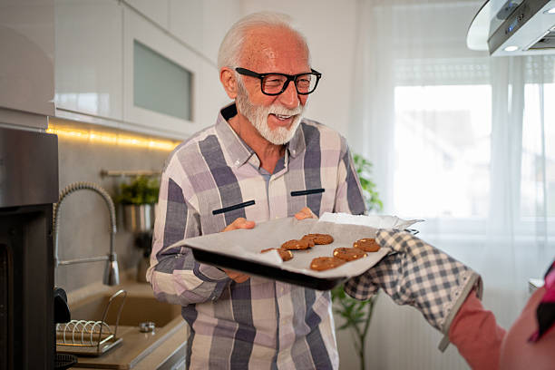 istock Senior man holding baking pan with freshly baked cookies in kitchen 2220467420