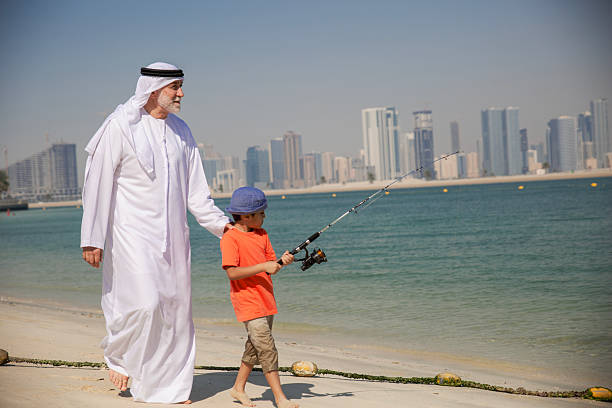 istock Arab grandfather and little boy having fun at beach 2220467728