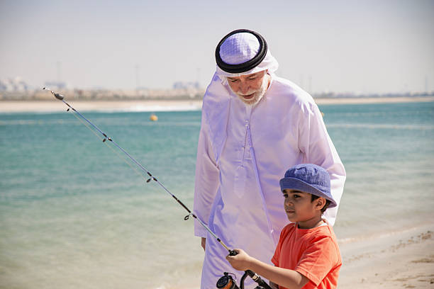 istock Arab grandfather and little boy having fun at beach 2220467776
