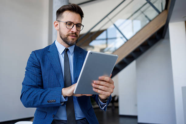 istock Focused businessman working diligently on a digital tablet while seated in a sleek, modern office environment, embodying professionalism 2220468187