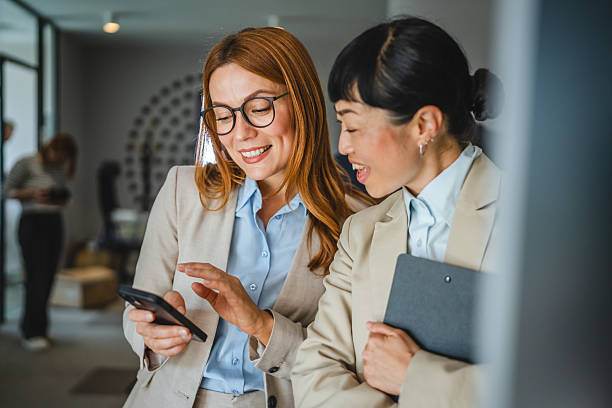 istock two multicultural female colleagues enjoy on break and use cellphone 2220469153