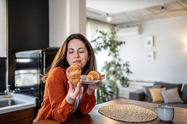 istock Woman enjoying fresh croissant in modern kitchen during breakfast time 2220472414