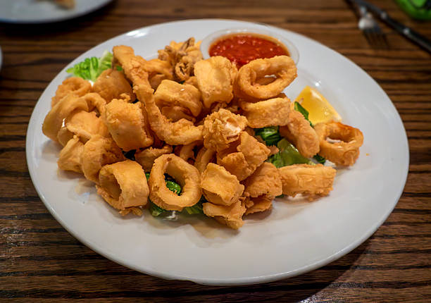 istock A white plate of golden fried calamari. 2220479038