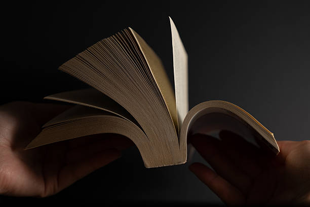 istock Hands holding open book on dark background promoting reading and personal growth 2220479324