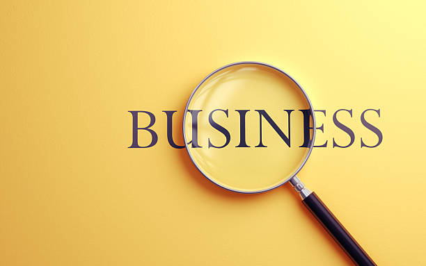 istock Business Text Selected with Metallic Magnifying Glass on Soft Yellow Background 2220479454