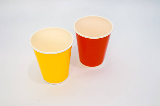 Two colorful paper cups, red and yellow, standing side by side on white background