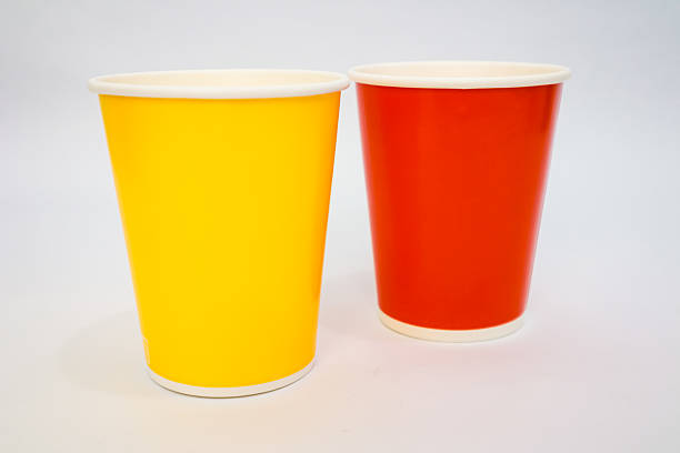 istock Two colorful disposable paper cups, yellow and red, stand on a white background, studio shot 2220480035