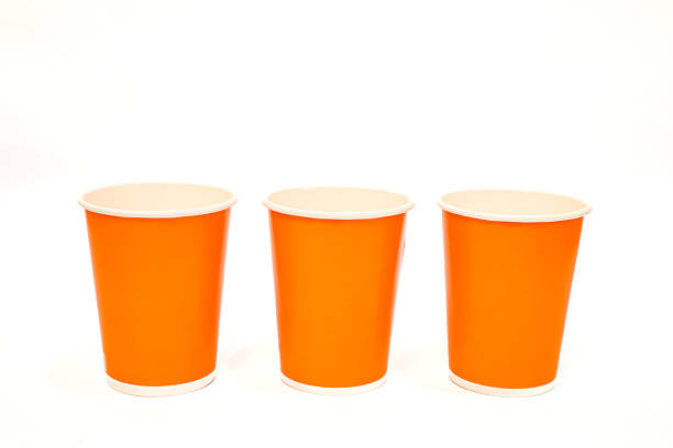 istock Three vibrant orange paper cups arranged against a clean white background, studio shot 2220480289