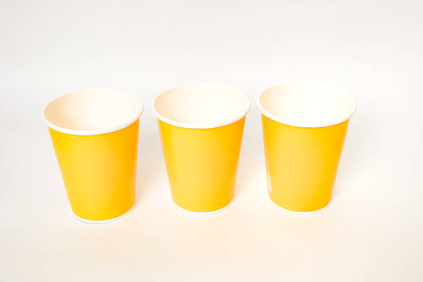 istock Three bright yellow disposable cups lined up against a clean white background 2220480511