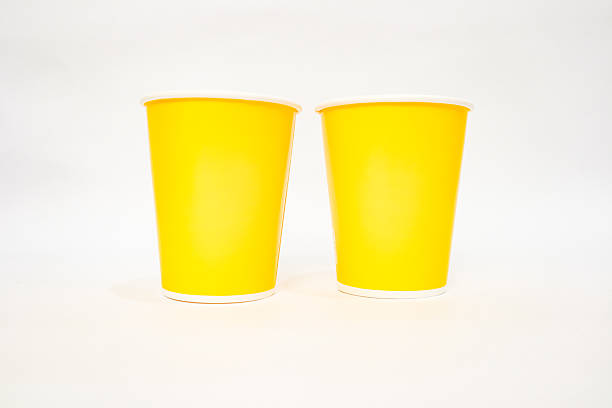 istock Two vibrant yellow paper cups sit side-by-side on a pristine white background 2220480517