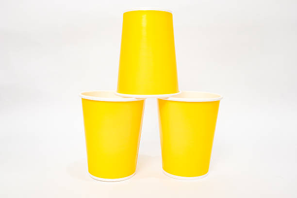 istock Bright Yellow Paper Cups Stacked in a Pyramid Formation on White Background 2220480584