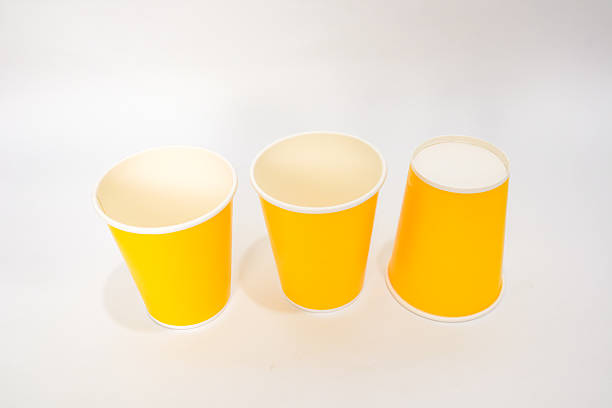 istock Three vibrant yellow paper cups arranged on a clean white surface, offering a simple and modern aesthetic 2220481188