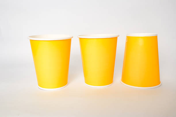 istock Three yellow paper cups on a white surface evoke a sense of simple utility 2220481191