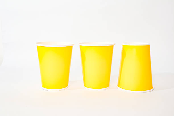 istock Three vibrant yellow disposable cups arranged on a clean, bright white surface 2220481204
