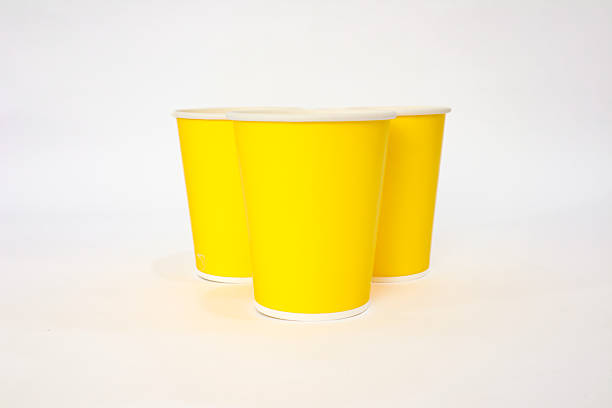 istock Three yellow paper cups isolated on white background, studio shot with soft light and minimalist composition 2220481205