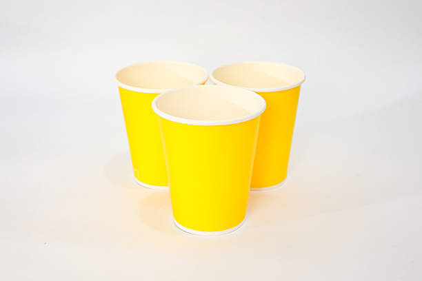 istock Three bright yellow paper cups arranged on a clean white surface, creating a minimalist and vibrant composition 2220481250