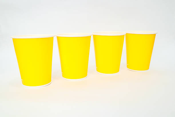 istock Four vibrant yellow disposable paper cups arranged in a row against a white backdrop 2220481314