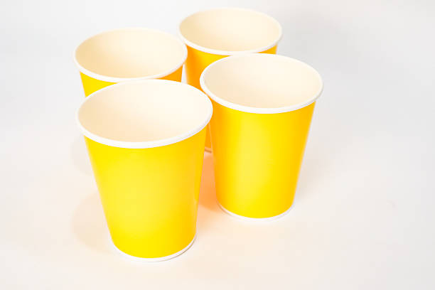 istock Four yellow paper cups arranged on a white surface in a studio setting 2220481315