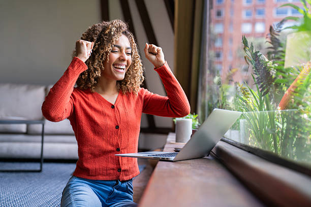 Successful woman working at home and celebrating an achievement