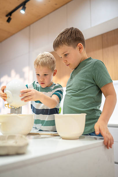 istock Caucasian Brothers Joyfully Mixing Cookie Dough in Kitchen 2220485032