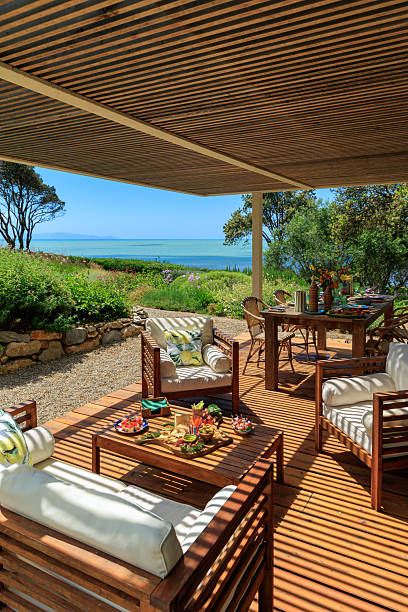 3d rendering of wooden patio with comfortable bed at sand beach in front of palm trees