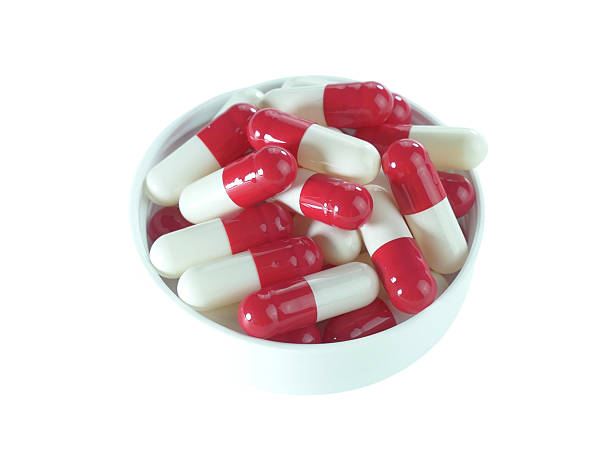 istock Red and white capsule pills in a white tray isolated on white background. 2220496496