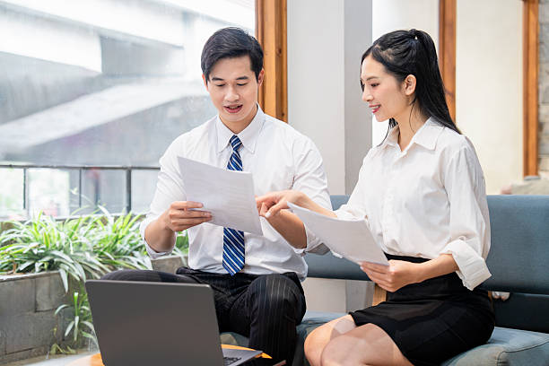 istock Two business people review documents together discussing information on printed papers in the office 2220503504