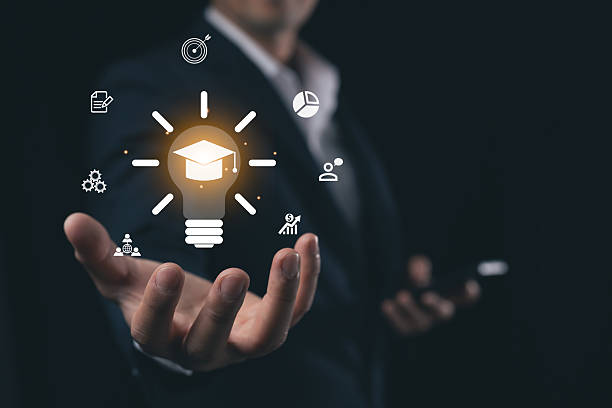 istock Business Professional Holding Light Bulb with Graduation Cap Icon, Symbolizing Ideas, Innovation, Success, and Education in Modern Corporate Environment 2220503678