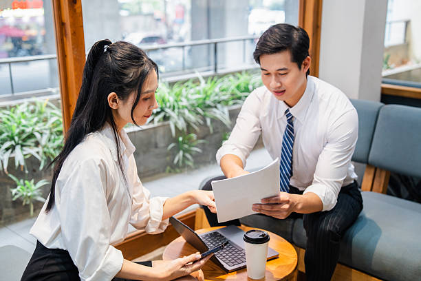 istock Asian colleagues collaborate on a project at a cafe using a laptop and review documents together 2220503704