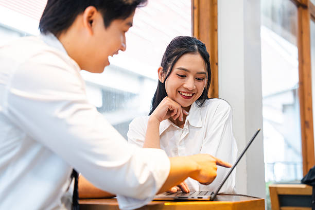 istock Young professionals collaborate at a desk with one pointing to a laptop screen and smiling 2220503787