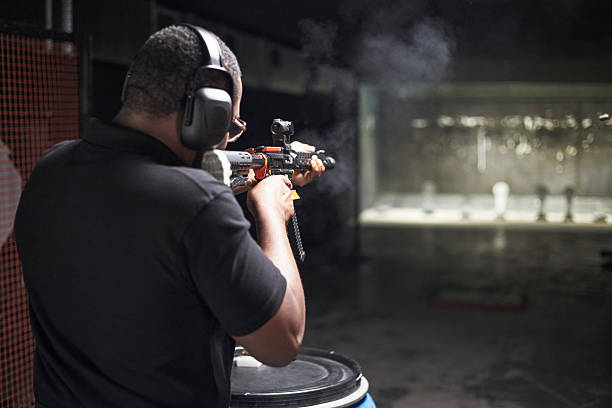 istock Black Man Firing Rifle at Indoor Shooting Range 2220504569