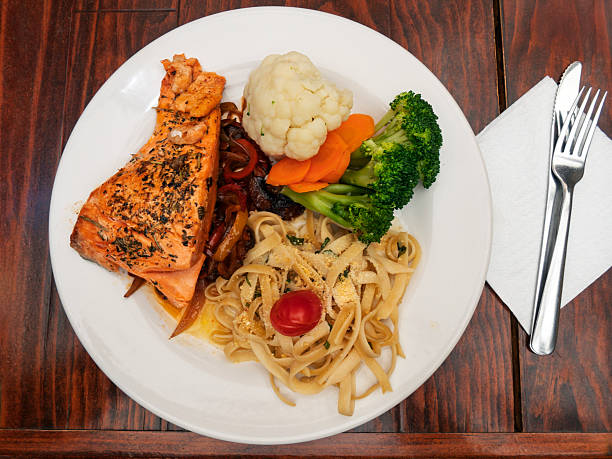 istock Delicious salmon dish served with vegetables and pasta in a cozy dining setting 2220504604