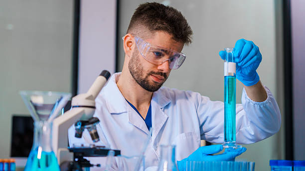 istock Young Caucasian male scientist works in laboratory, analyzing chemical samples with glassware and microscope. research tools, experiments, data interpretation, pharmaceutical development. 2220505637