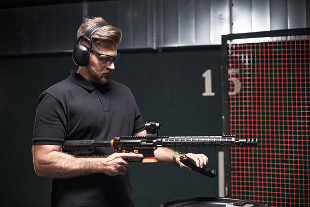 istock Young Caucasian Man Loading Rifle Magazine at Indoor Shooting Club Range 2220505837