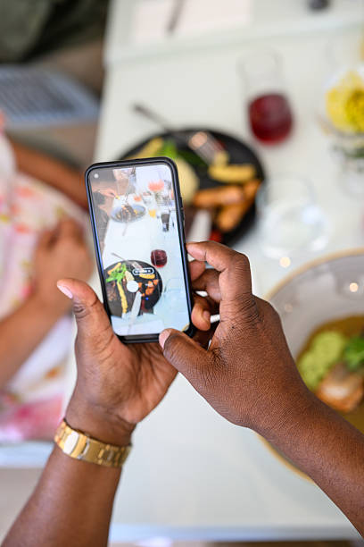 istock Closeup of hands photographing a blurred restaurant table with meals using a smartphone 2220506176