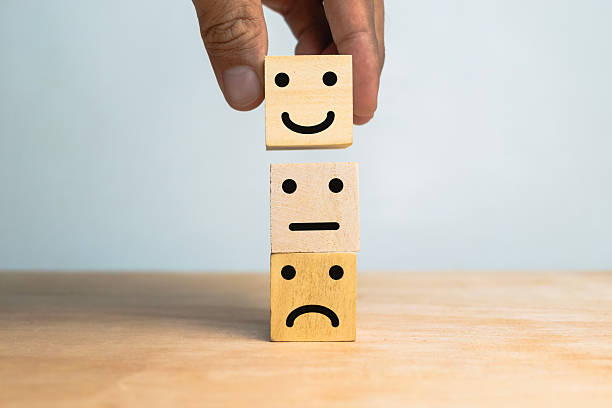 istock male hand stack sad, flat and happy face expression emoticon on wooden cubes on wooden table 2220506431