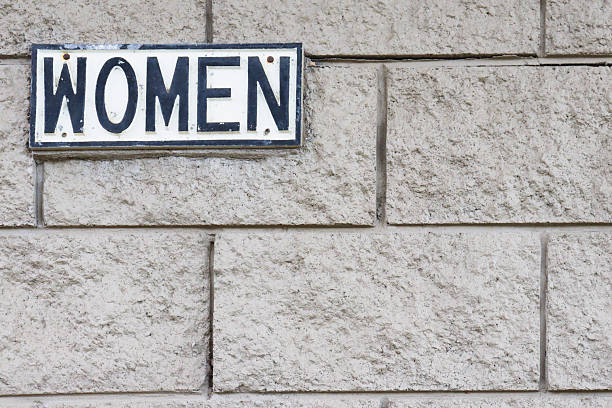 istock women sign on grey brick restroom wall 2220507237