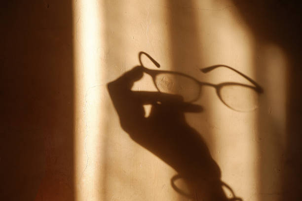 istock Shadow of hand holding glasses on wall with dramatic light 2220510960