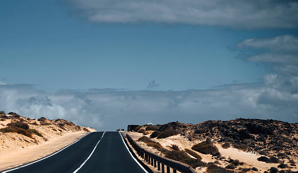 istock An asphalt road among desert with sandy dunes. 2220519110