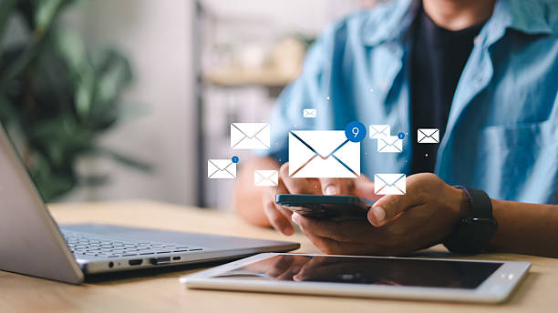 istock Person checking smartphone with email icons floating above. Concept of digital communication, mobile inbox, real-time notification, and online message system. 2220524607