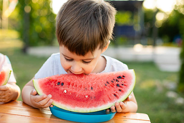 istock Adorable Kid with Watermelon Slice at Picnic Table 2220525814